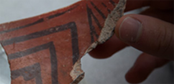 person holding a piece of broken pottery